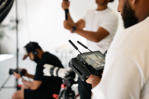 Director monitoring wireless video feed on set with crew filming in studio