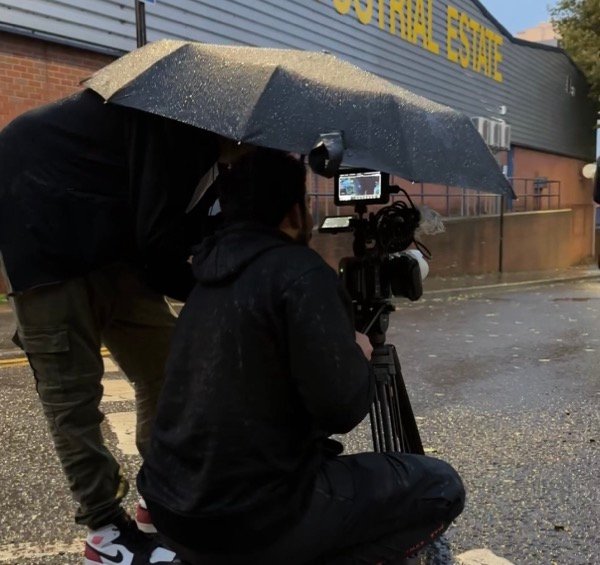 Filming on location in the rain with cinema camera and umbrella