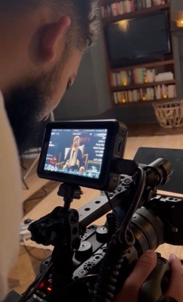 Cameraman reviewing interview footage on monitor during indoor shoot