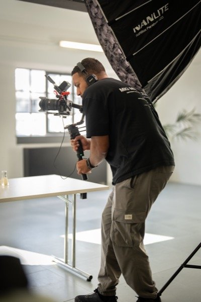 Cameraman with headphones filming in studio with softbox lighting