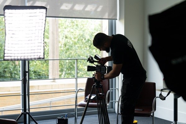 Videographer setting up camera and lighting for corporate interview